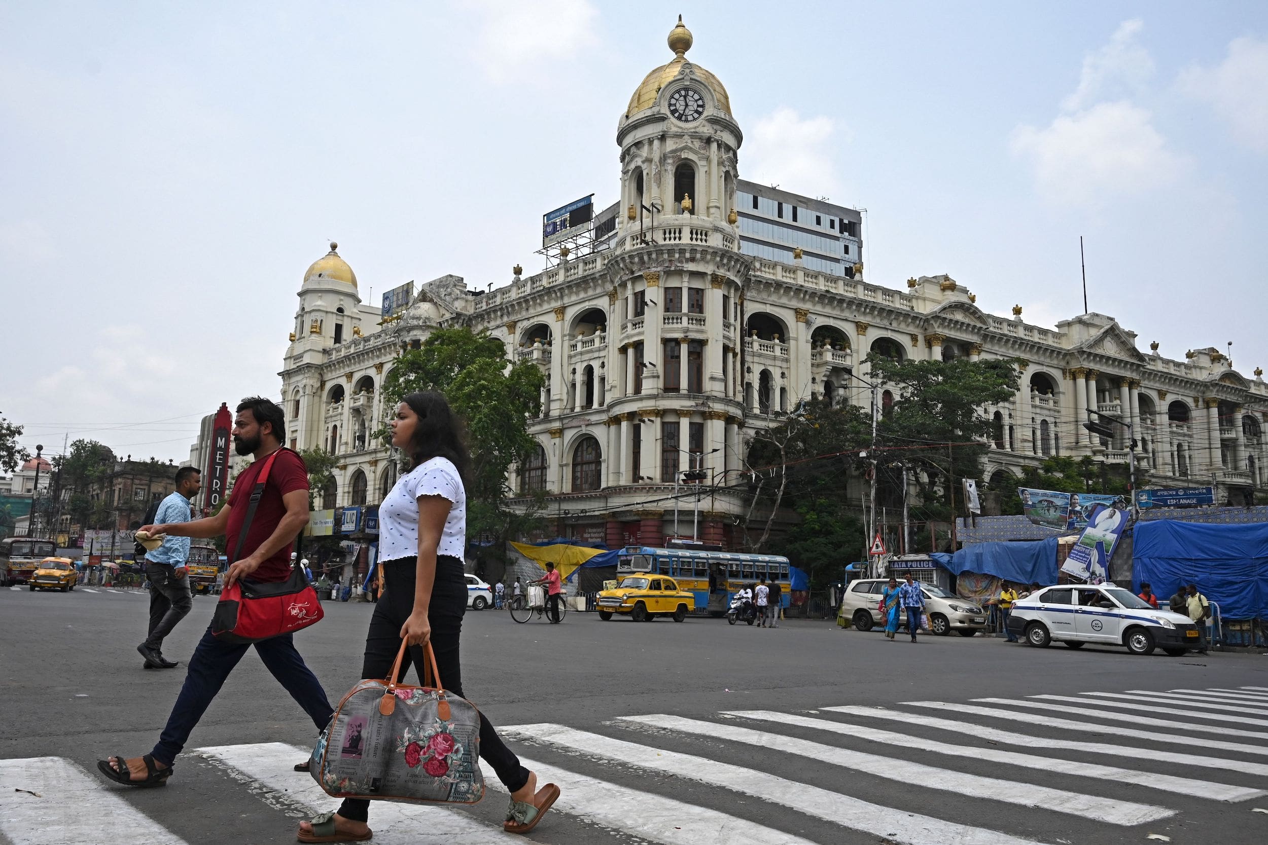 Commuters walk across a busy road in Kolkata